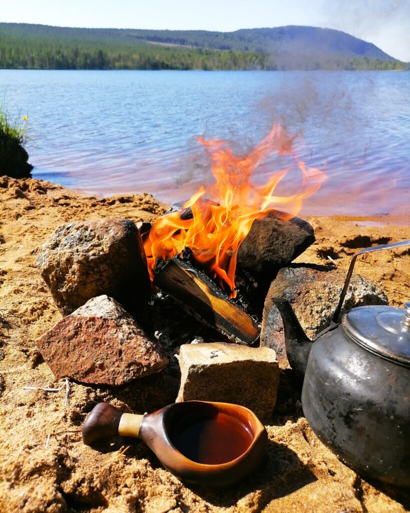 coffee kuksa mug WITH COFFEE and a campfire in nature